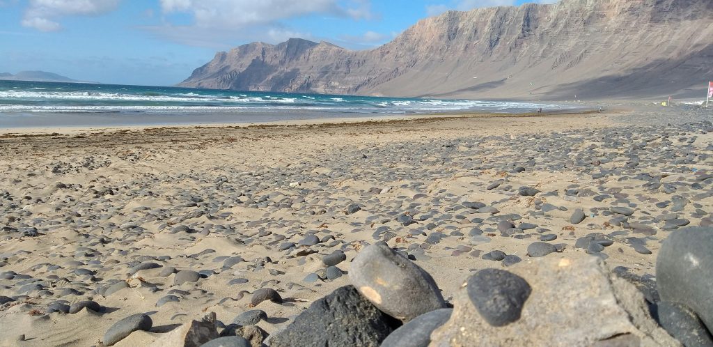 Natural undeveloped beach in the Canary Islands with rugged coastline, minimal buildings, and wild Atlantic ocean