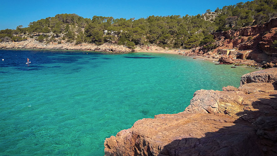 Cala Saladeta beach in Ibiza with turquoise water, rocky cliffs, and natural surroundings