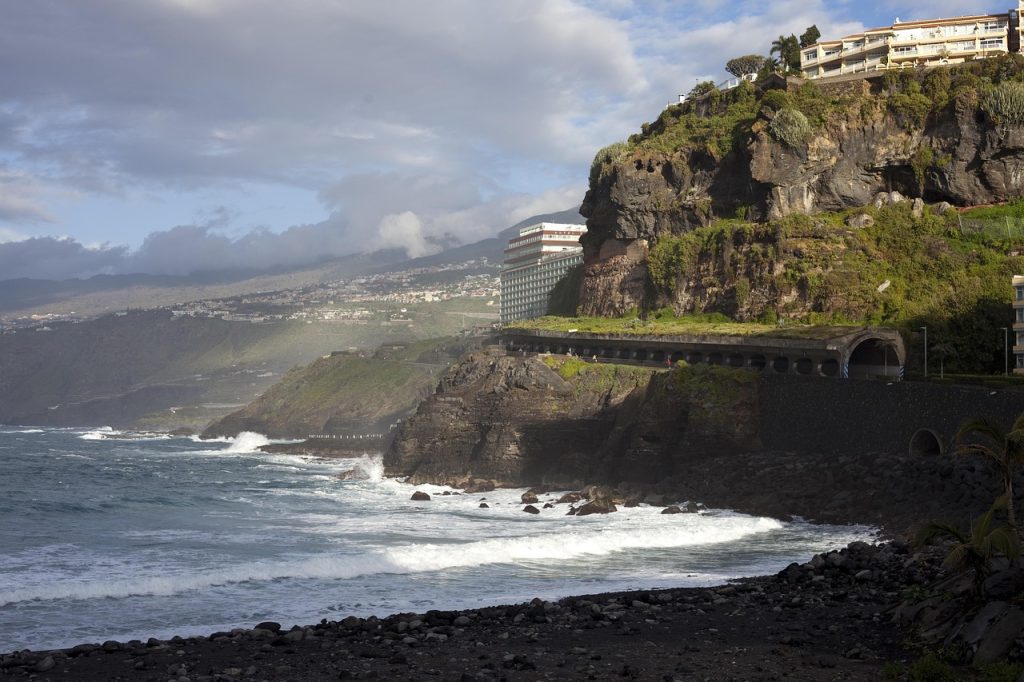 Black volcanic sand beach in Tenerife with dark lava sand, waves, and dramatic coastal scenery