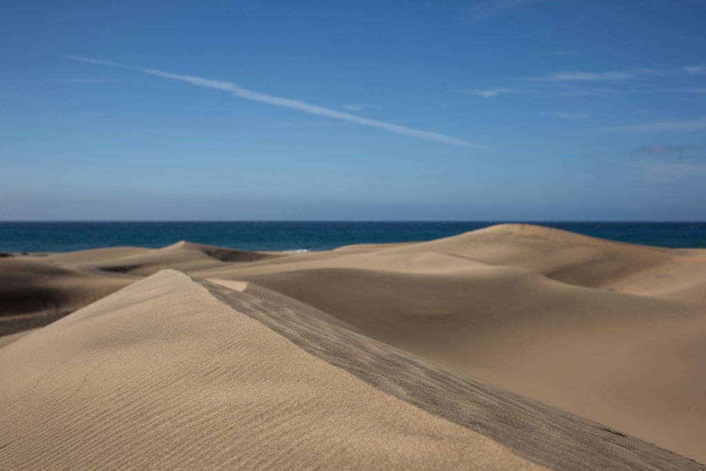 Maspalomas sand dunes in Gran Canaria with golden desert landscape meeting the Atlantic Ocean