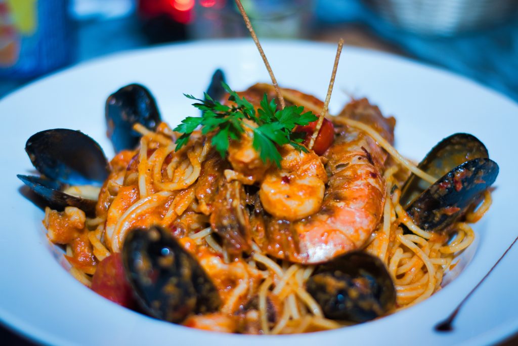 Italian seafood pasta with mussels, shrimp, and clams served in a tomato and olive oil sauce by the coast