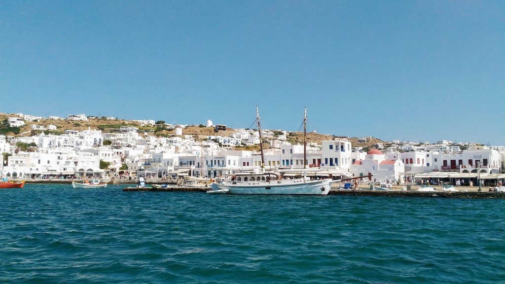 Mykonos island in Greece with white Cycladic houses, turquoise Aegean Sea, golden beaches, windmills, and vibrant summer atmosphere.