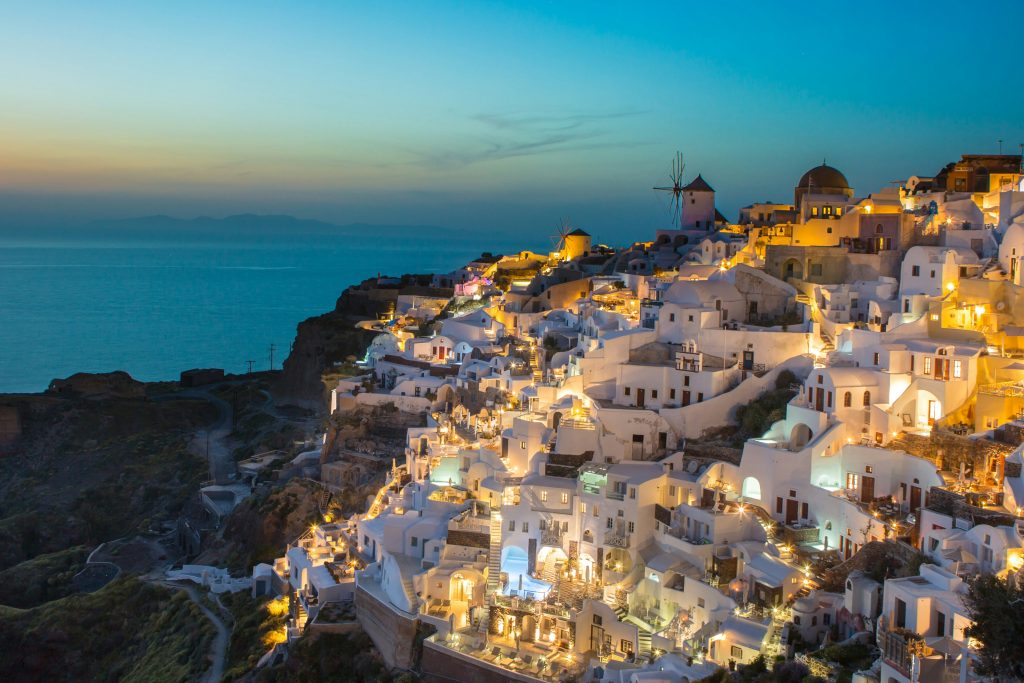 Oia village in Santorini with white houses and blue domes overlooking the Aegean Sea at sunset