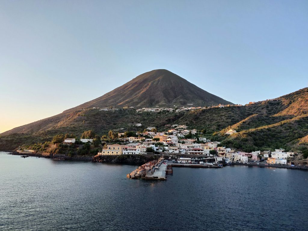 Aeolian Islands off the coast of Sicily, showing dramatic volcanic landscapes with black sand beaches, rugged coastlines, and the active Stromboli volcano rising above the sea, highlighting the islands’ wild and remote character