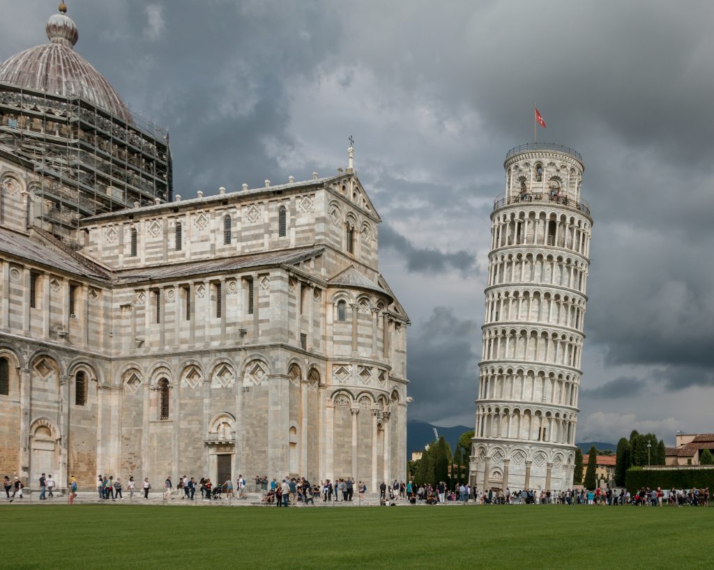 Leaning Tower of Pisa in Piazza dei Miracoli with cathedral and green lawns in Tuscany