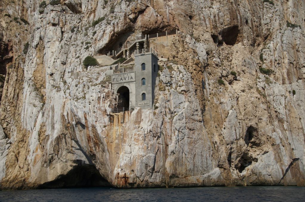 Porto Flavia mining complex carved into sea cliffs in Sardinia, showing historic tunnels and platforms overlooking the Mediterranean Sea