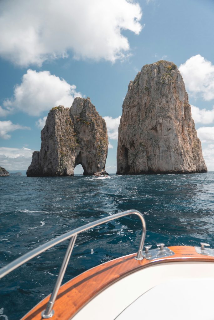 Boat approaching the island of Capri from the Amalfi Coast, featuring dramatic cliffs, turquoise water, and the iconic Mediterranean landscape.