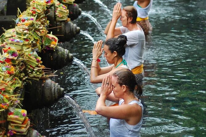 Traditional Balinese water purification ritual at temple with offerings and spiritual cleansing in natural setting
