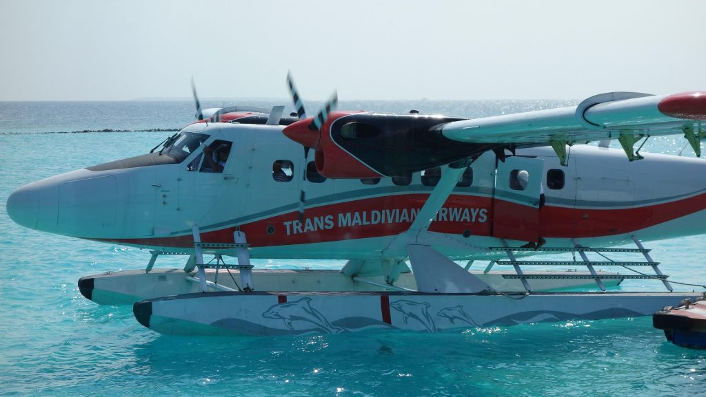 Maldives seaplane landing on turquoise lagoon near tropical islands and overwater villas
