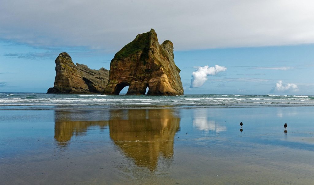 Wharariki Beach in New Zealand featuring dramatic rock formations and wild South Island coastline