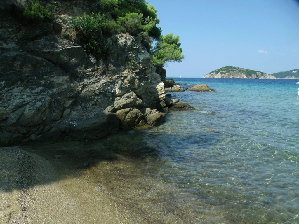 Lalaria Beach in Skiathos with white limestone cliffs, crystal-clear blue water and natural rock arch