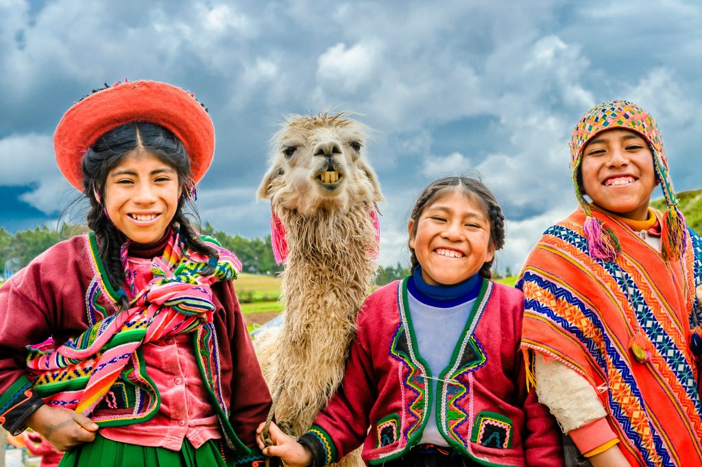 Llama with local people in traditional clothing Peru travel guide