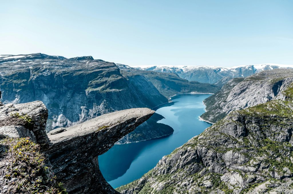 Dramatic cliff viewpoint overlooking a deep fjord with steep mountains and clear blue water