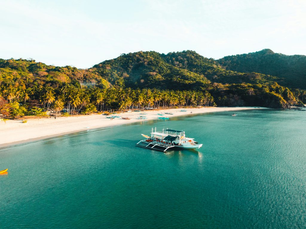 tropical beach in palawan philippines with turquoise water, palm trees, and traditional boat