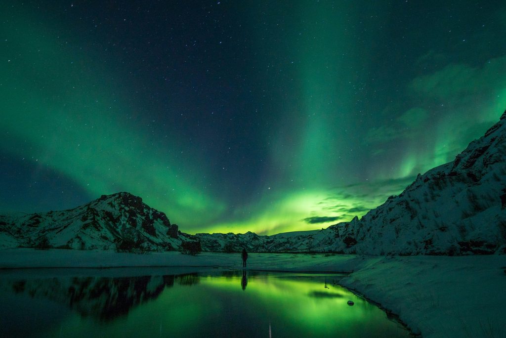 Northern Lights in Iceland over mountains and night sky – Iceland travel guide