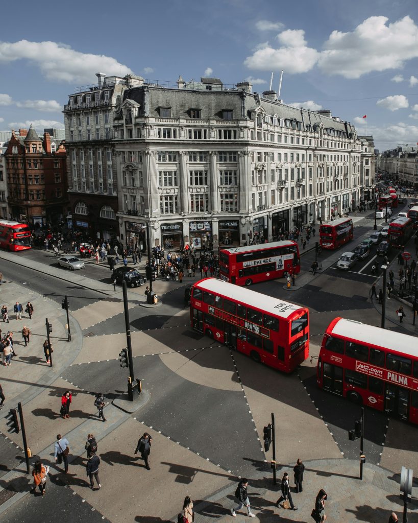busy London street with red double decker buses and people crossing at an intersection