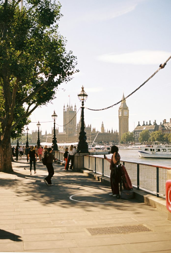 people walking along the Thames river with London skyline and bridges