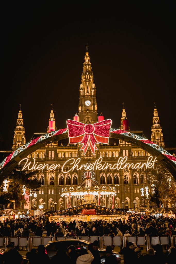 Vienna Christmas market with festive lights, wooden stalls and people walking around