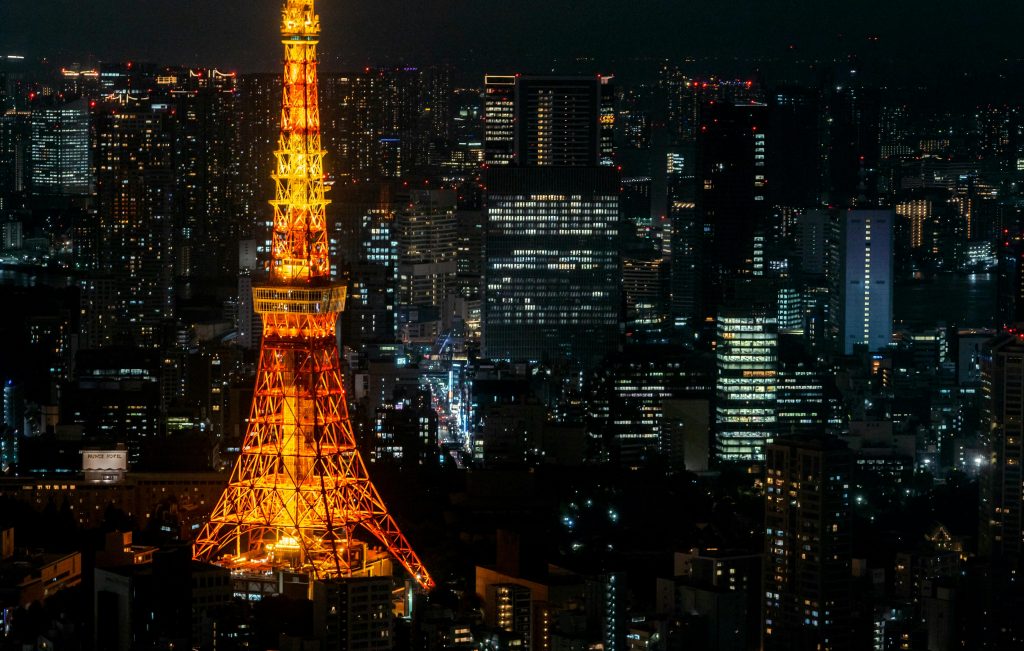 Tokyo Tower illuminated at night with city skyline and buildings surrounding it