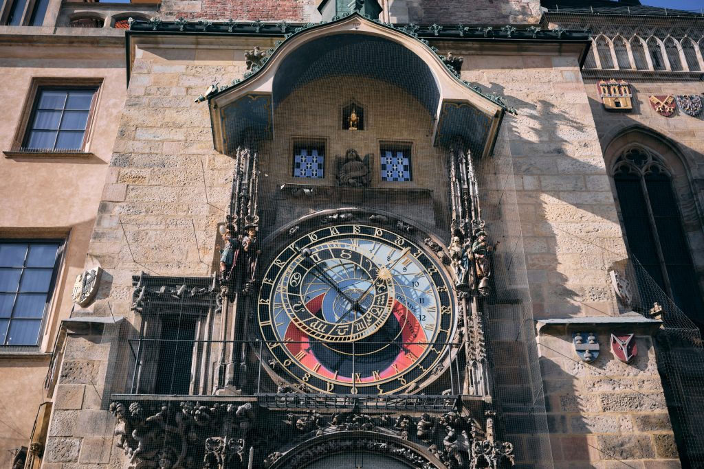 Detailed medieval clock with ornate carvings, zodiac dial, and historic stone facade in the old town.