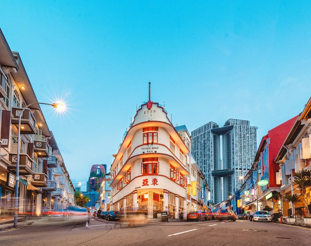 Colorful heritage street with traditional shophouses, modern skyscrapers, and lively city atmosphere in Singapore