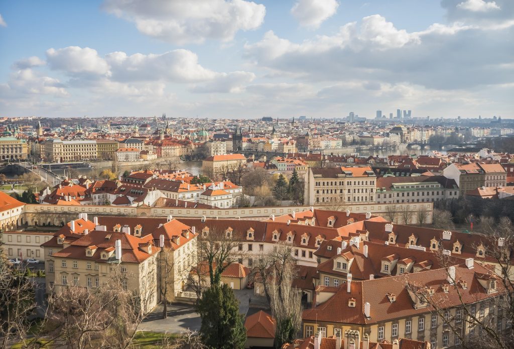 Panoramic city skyline with red rooftops, historic buildings, river views, bridges, and wide scenic views across the old city.