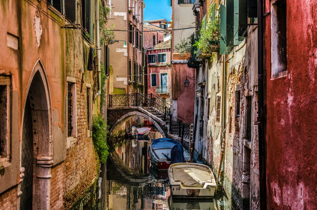 Quiet canal with small bridge and historic alleyway in Venice, Italy