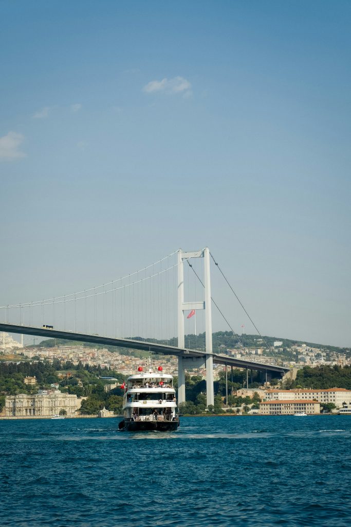 Passenger ferry crossing the Bosphorus with a suspension bridge and calm blue water in the background.