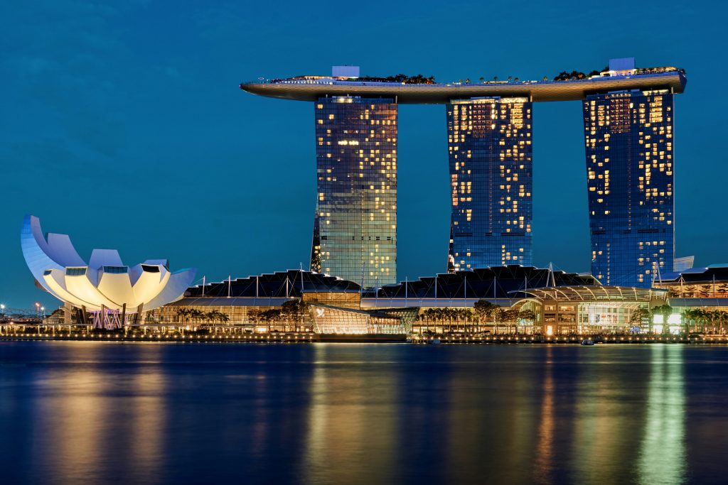 Night view of Marina Bay skyline with illuminated skyscrapers and reflections on the water