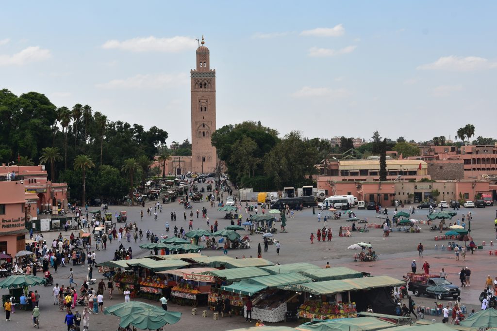 Crowds and market stalls in Jemaa el-Fnaa square with Koutoubia Mosque in the background