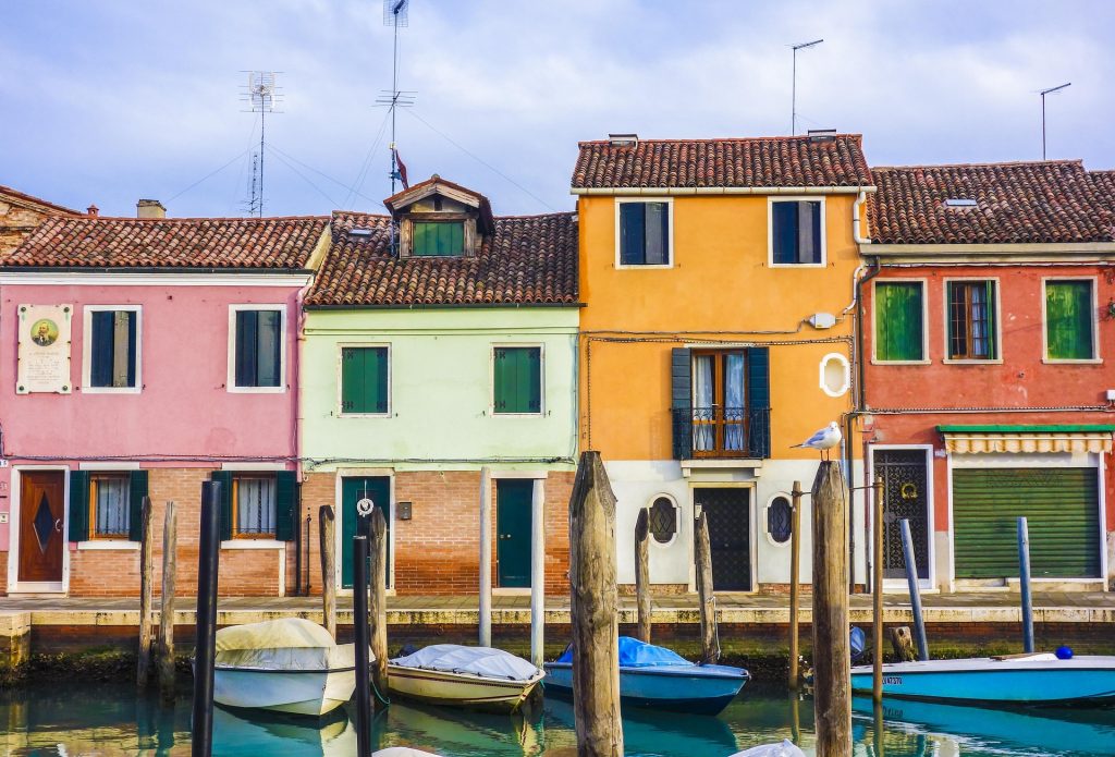 Colorful waterfront houses and small boats along a canal in Venice, Italy
