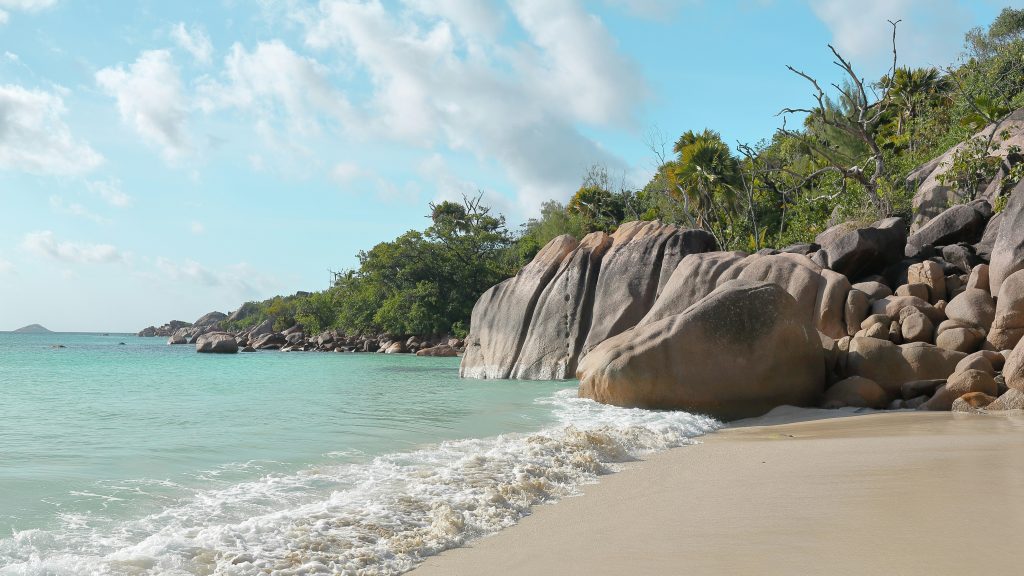 Granite boulders along the shoreline of Anse Lazio beach with clear turquoise water and soft white sand in Seychelles