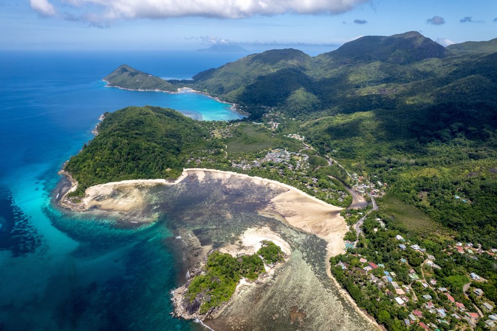 Aerial view of the Seychelles coastline with turquoise waters, sandy beaches, and lush green mountains